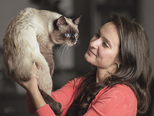 Woman holding a Siamese cat